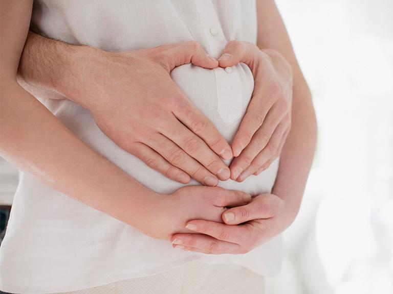 Rodzice trzymają dłonie na brzuchu kobiety w ciąży