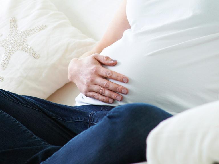 Kobieta w ciąży trzyma dłoń na brzuchu